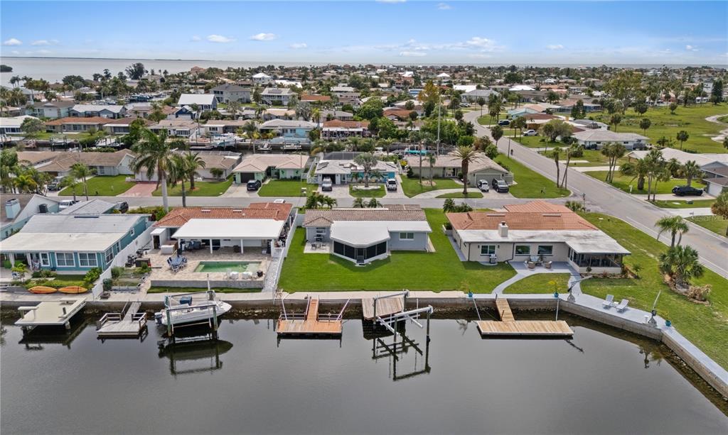 An aerial view shows three waterfront houses with private docks along a canal — 5008 DORY DRIVE, NEW PORT RICHEY, FL