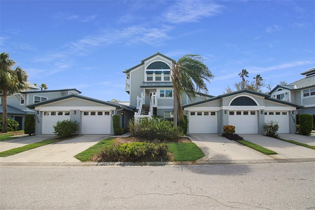 A multi-unit residential building features two white garage doors and a central elevated entryway — 1206 SIESTA BAYSIDE DRIVE UNIT 1206B, SARASOTA, FL