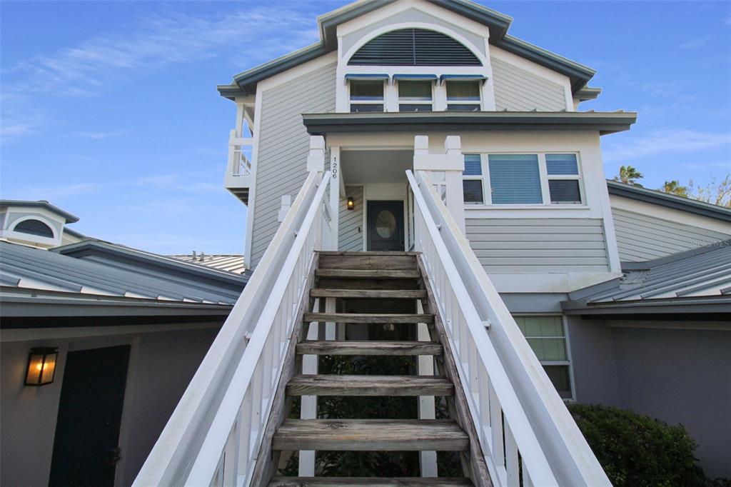 A wooden staircase leads up to the elevated front entrance of a multi-story coastal home — 1206 SIESTA BAYSIDE DRIVE UNIT 1206B, SARASOTA, FL