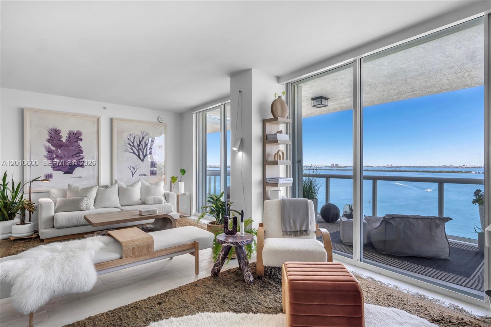 A living room features a white sofa, an armchair, and floor-to-ceiling windows overlooking the ocean — 10 Venetian Way # 1803, Miami Beach FL 33139, MIAMI BEACH, FL