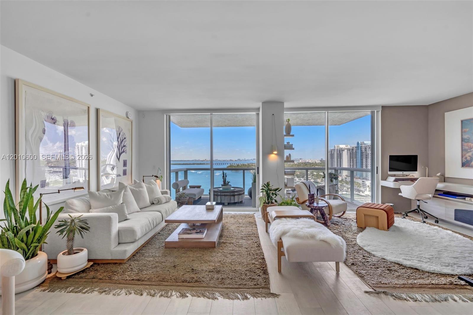 A bright living room features a sofa, desk, and floor-to-ceiling windows overlooking the ocean — 10 Venetian Way # 1803, Miami Beach FL 33139, MIAMI BEACH, FL