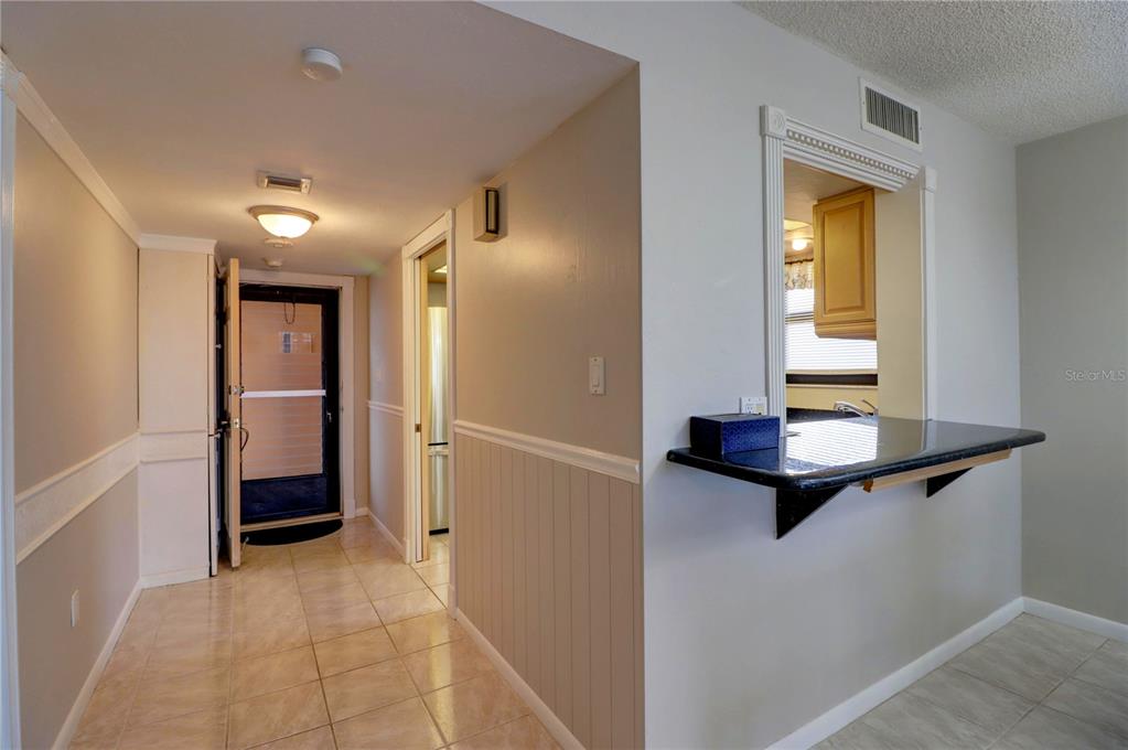 A tiled entryway leads to a front door and a kitchen pass-through with a counter — 4260 SE 20TH PLACE UNIT 801, CAPE CORAL, FL