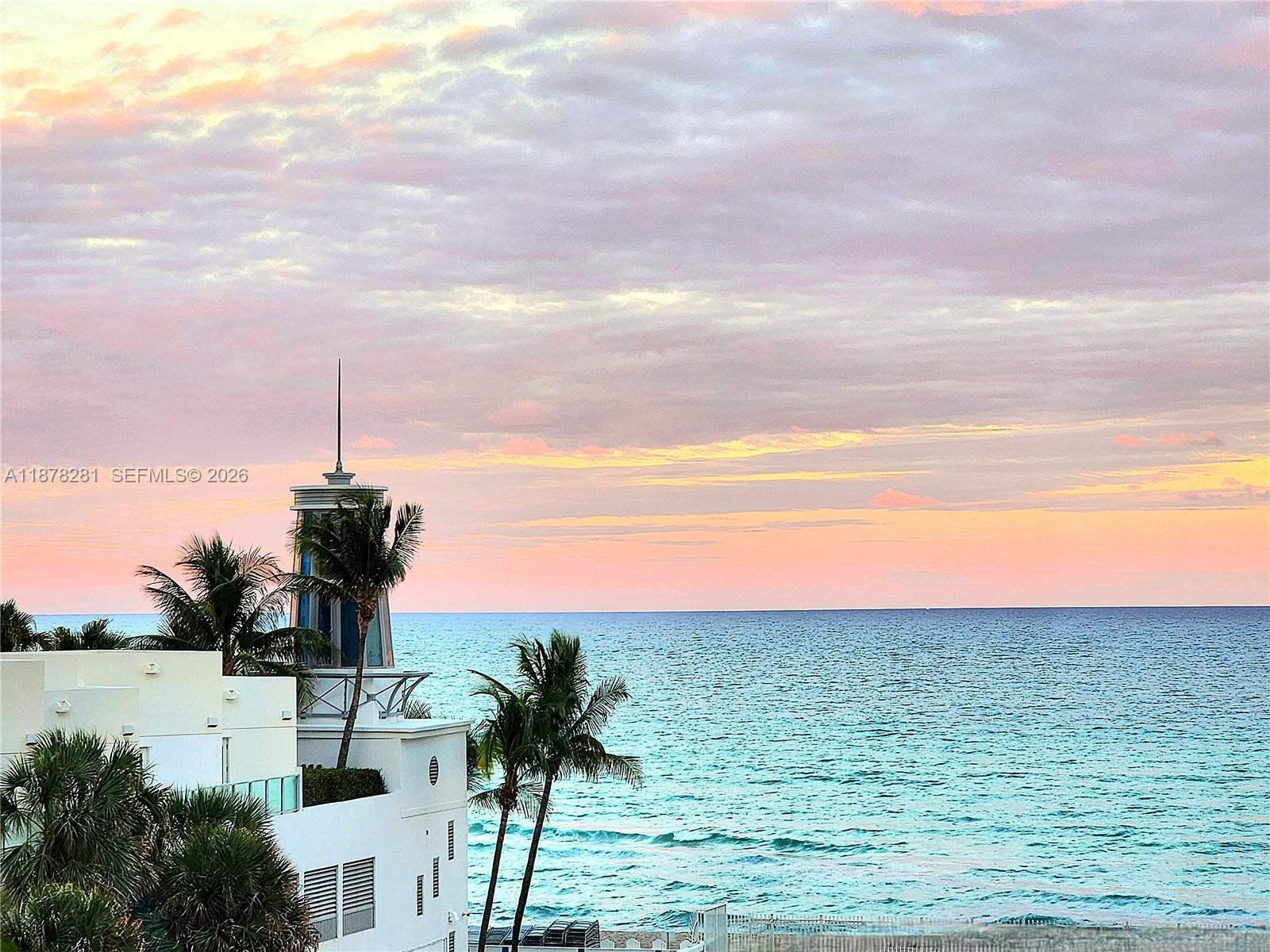 An exterior view of a white building with a tower overlooking the ocean at sunset — 3505 S Ocean Dr # 1006, Hollywood FL 33019, HOLLYWOOD, FL