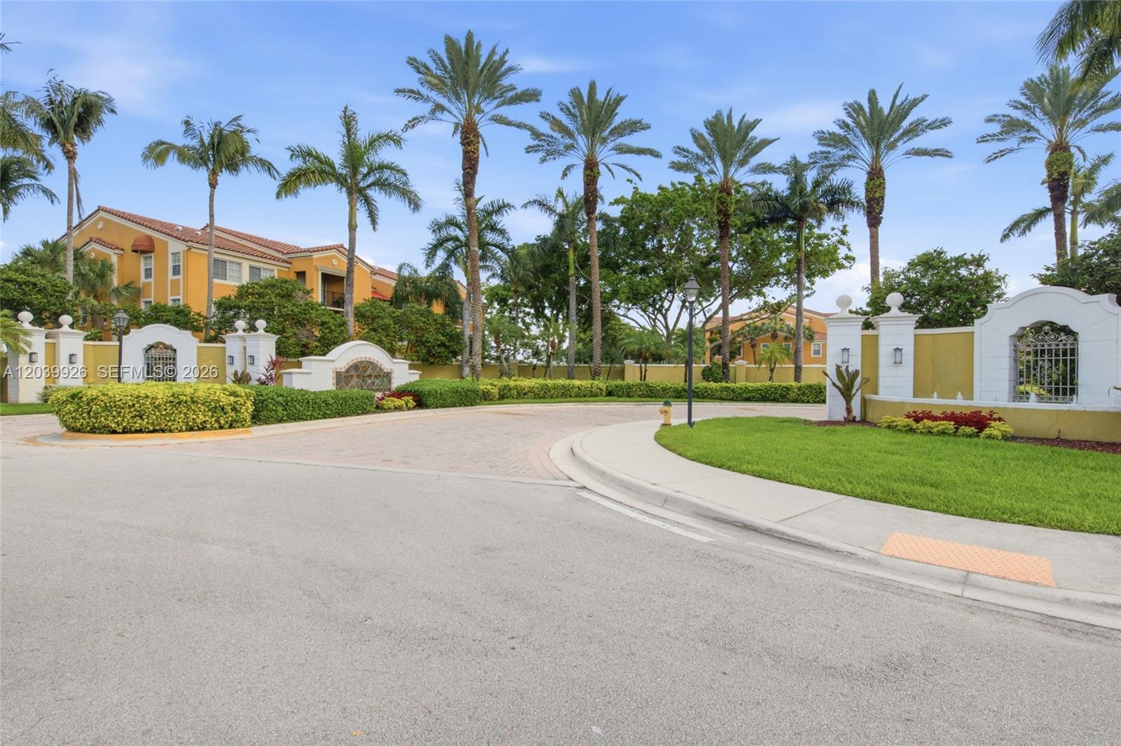 The exterior view shows a gated entrance with palm trees and yellow apartment buildings — 2351 W Preserve Way # 306, Miramar FL 33025, MIRAMAR, FL