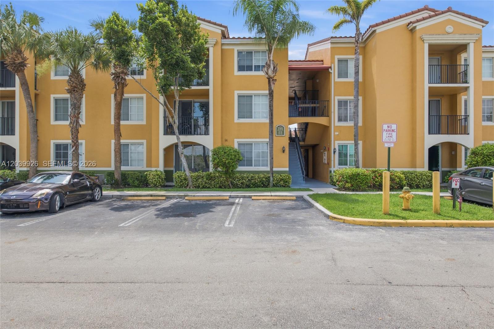 A three-story yellow apartment building with a parking lot and palm trees in front — 2351 W Preserve Way # 306, Miramar FL 33025, MIRAMAR, FL