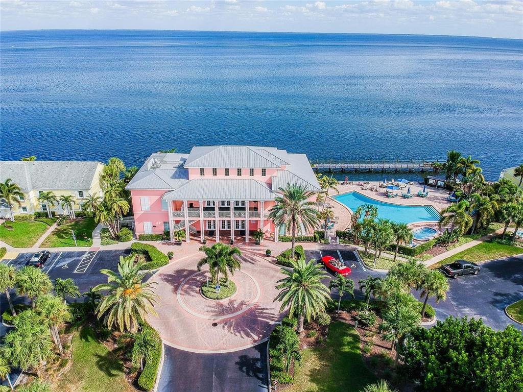 An aerial view of a pink waterfront building with a circular driveway and swimming pool — 4975 COBIA DRIVE SE UNIT A, ST PETERSBURG, FL