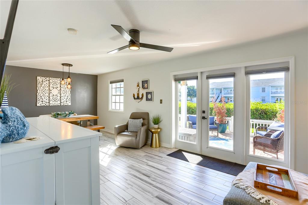 A bright living and dining area features wood-look tile floors, a ceiling fan, and glass doors — 4975 COBIA DRIVE SE UNIT A, ST PETERSBURG, FL