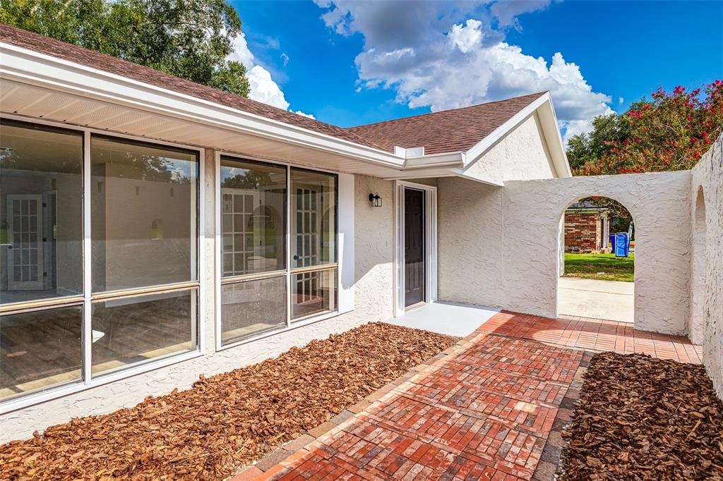 A brick walkway leads to the front entrance of a house with large glass windows — 4826 KIMBALL COURT W, LAKELAND, FL