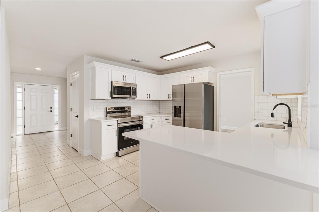 A kitchen with white cabinets, stainless steel appliances, and a white quartz peninsula countertop — 4826 KIMBALL COURT W, LAKELAND, FL