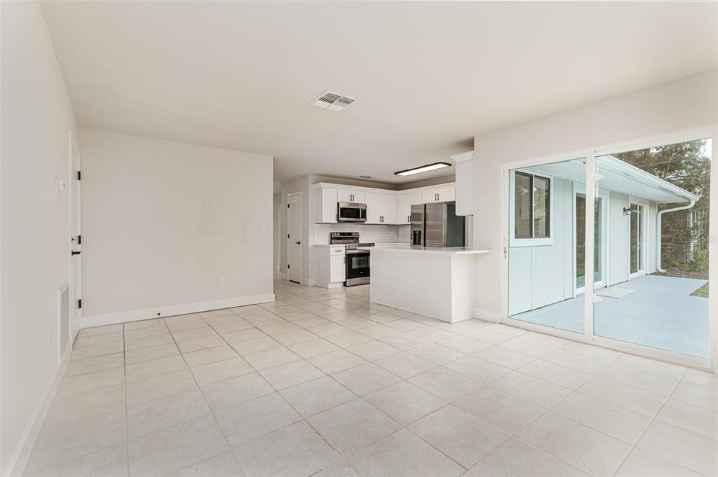 A bright kitchen with white cabinets and stainless steel appliances opens into a tiled dining area — 4826 KIMBALL COURT W, LAKELAND, FL