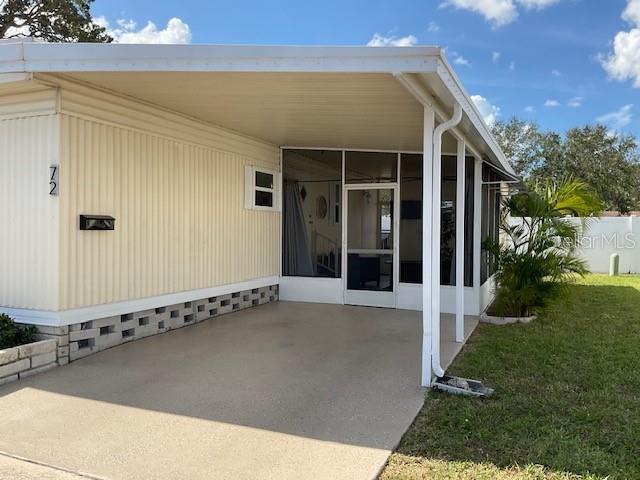 A mobile home exterior features a beige facade, a carport, and a screened-in porch — 72 PINDO PALM STREET W, LARGO, FL