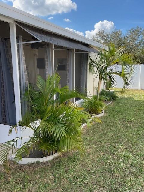 A screened-in porch with a metal awning overlooks a grassy yard with small palm trees — 72 PINDO PALM STREET W, LARGO, FL