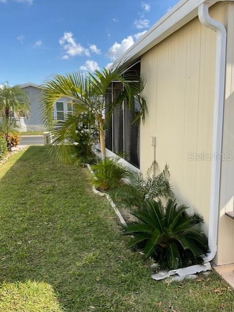 The exterior of a light-colored mobile home features a screened porch and small palm trees — 72 PINDO PALM STREET W, LARGO, FL