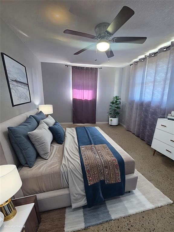 A bedroom features a bed with blue and gray bedding, a ceiling fan, and curtains — 3007 15TH STREET W, BRADENTON, FL