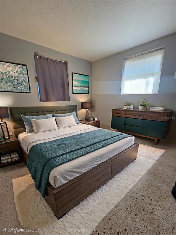 A bedroom features a bed with a teal throw, a wooden dresser, and two windows — 3007 15TH STREET W, BRADENTON, FL