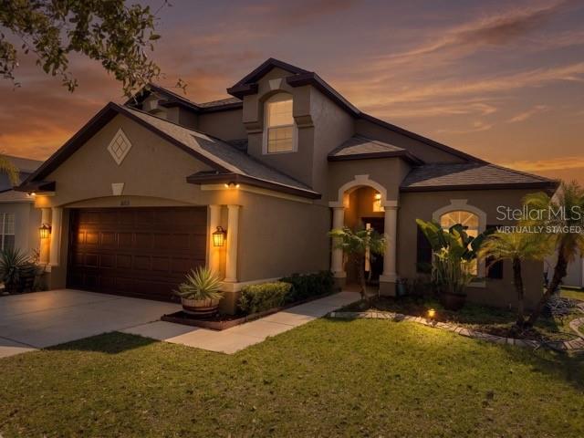 A two-story house with a brown garage and tan stucco exterior at sunset — 8103 TAR HOLLOW DRIVE, GIBSONTON, FL