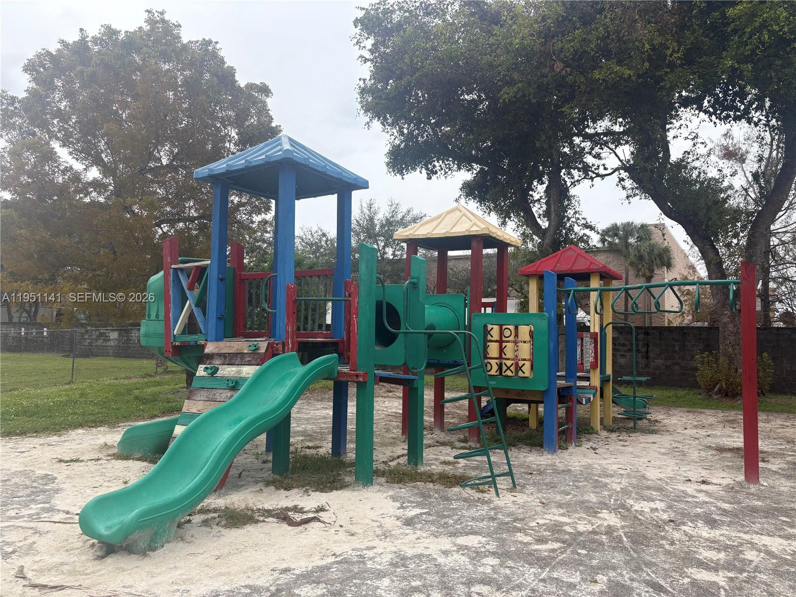 A colorful outdoor playground structure with slides and climbing equipment sits on a sandy lot — 8026 SW 21st Ct # 8026, Miramar FL 33025, MIRAMAR, FL