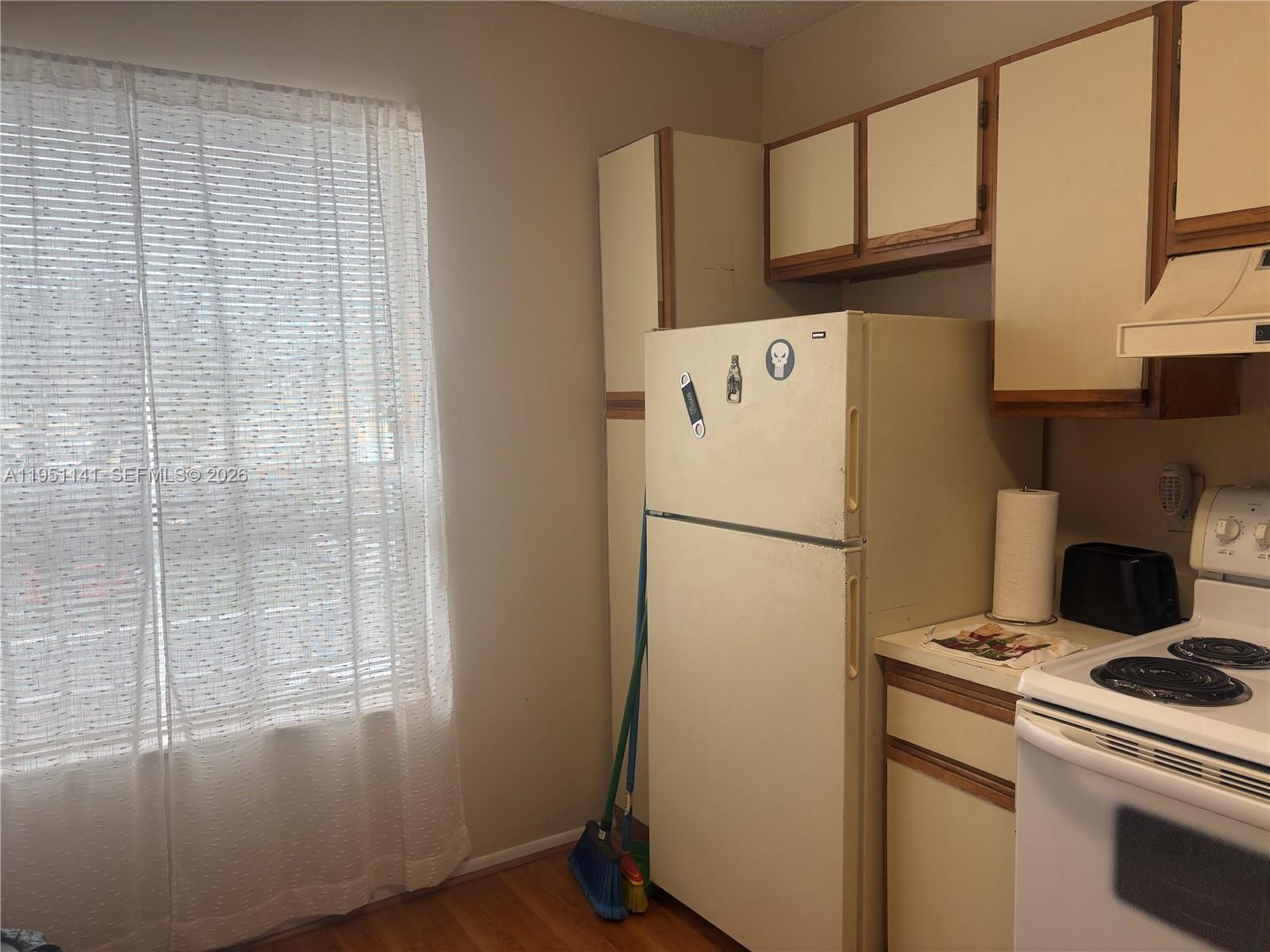 A kitchen features a white refrigerator, wooden cabinets, and a window with sheer curtains — 8026 SW 21st Ct # 8026, Miramar FL 33025, MIRAMAR, FL