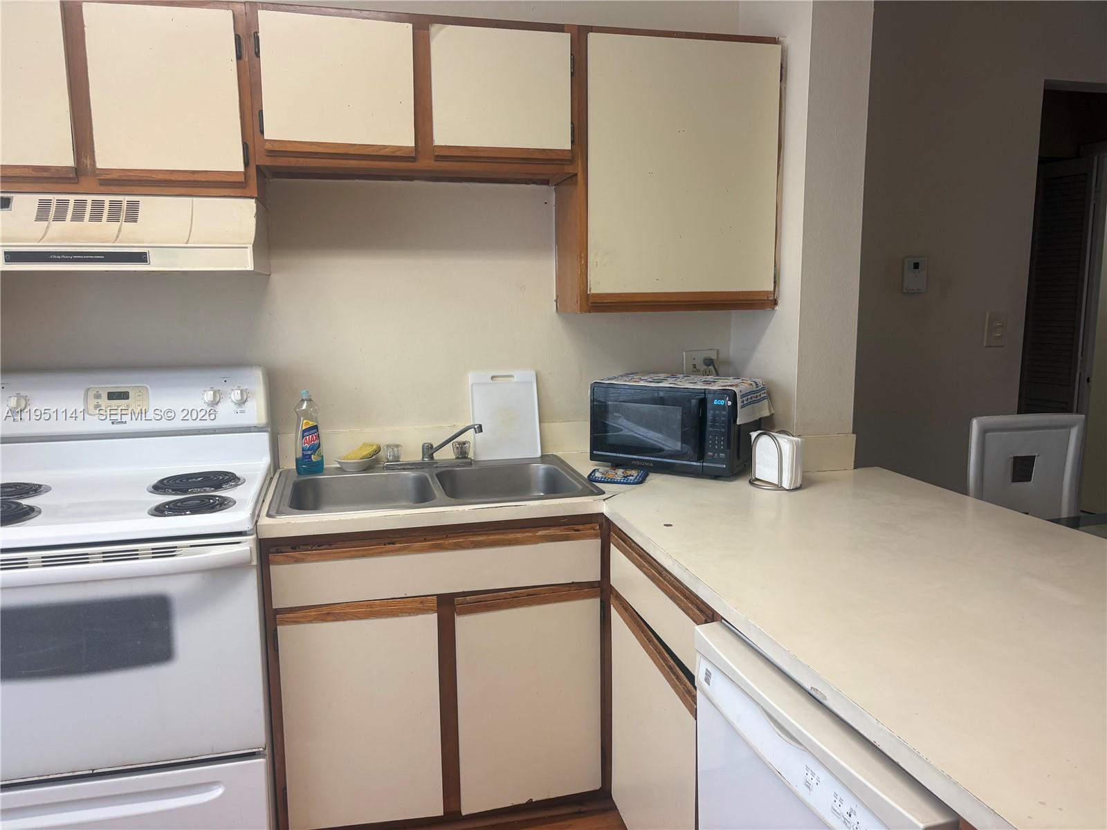 A kitchen features white appliances, a double-basin stainless steel sink, and light-colored cabinets with wood trim — 8026 SW 21st Ct # 8026, Miramar FL 33025, MIRAMAR, FL