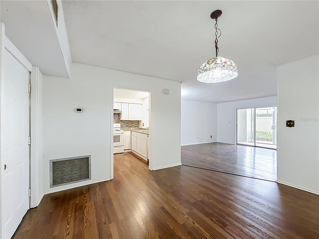 A dining area with wood flooring leads to a kitchen and a bright living room — 2837 NE 3RD STREET UNIT 103, OCALA, FL
