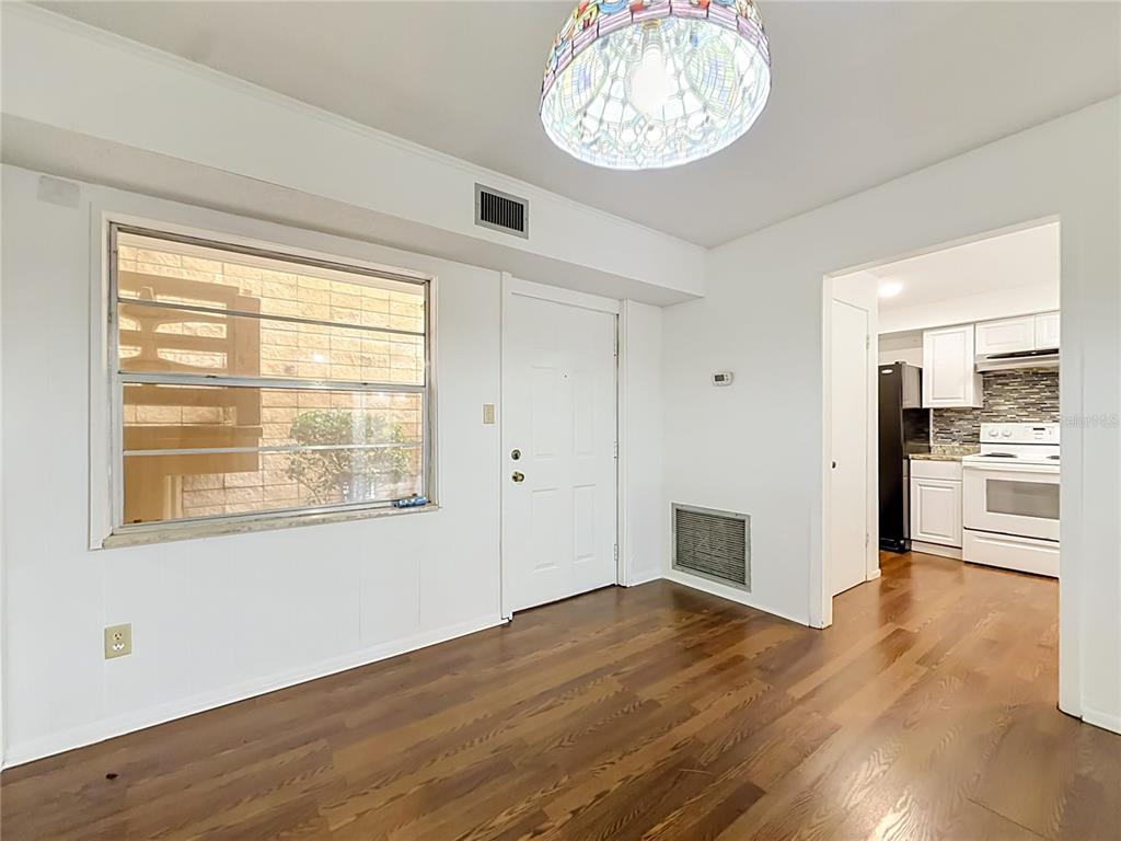 A room with wood-look flooring, a stained-glass light fixture, a window, and an adjacent kitchen — 2837 NE 3RD STREET UNIT 103, OCALA, FL