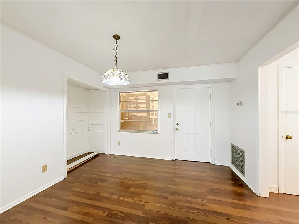 A room with wood-look flooring, a stained-glass pendant light, a window, and a white door — 2837 NE 3RD STREET UNIT 103, OCALA, FL