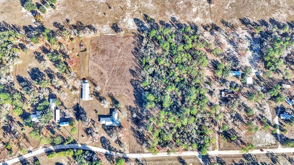 An aerial view shows a rural property with several buildings, a cleared field, and trees — 12151 SE 103RD LANE, DUNNELLON, FL