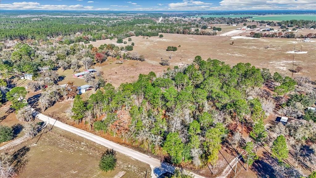 An aerial view shows a rural property with a wooded area, open fields, and buildings — 12151 SE 103RD LANE, DUNNELLON, FL