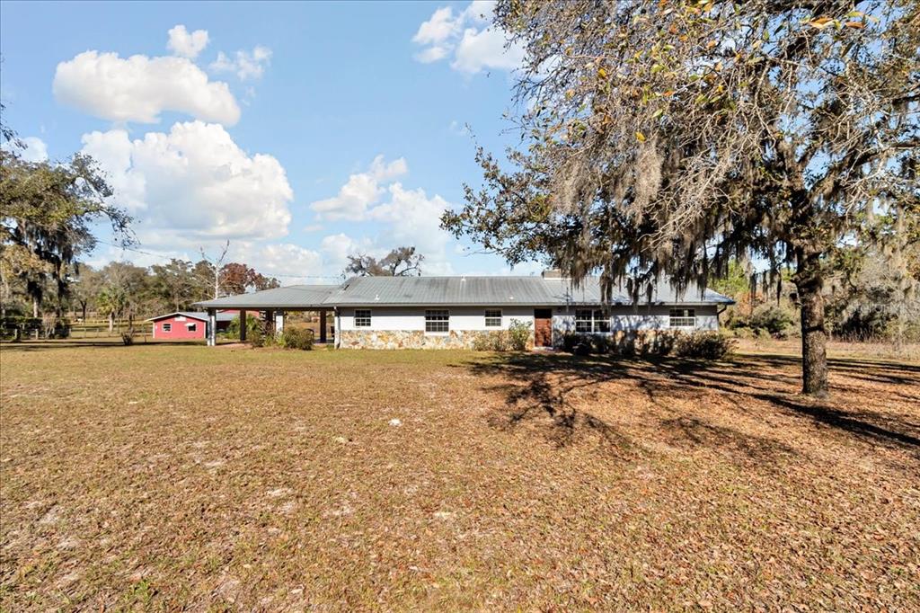 A single-story house with a metal roof and stone facade sits on a grassy lot — 12151 SE 103RD LANE, DUNNELLON, FL