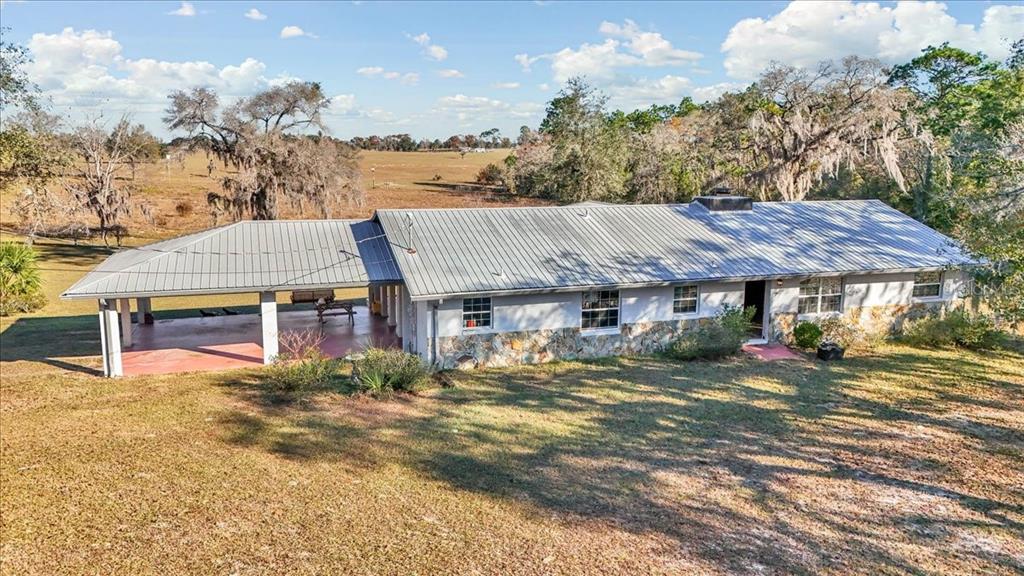 An exterior view of a single-story house with a metal roof and stone siding — 12151 SE 103RD LANE, DUNNELLON, FL