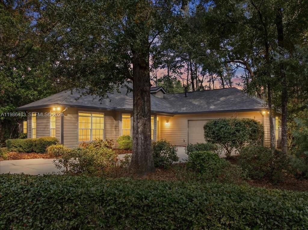 A single-story house with tan siding and a garage sits among mature trees — 4412 SW 101st Dr, Gainesville FL 32608, GAINESVILLE, FL