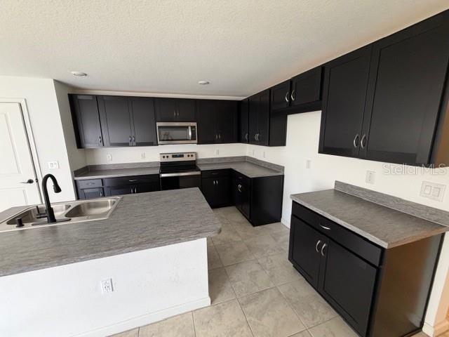 A kitchen features dark cabinets, grey countertops, a stainless steel oven, and a center island — 4815 RIGGING STREET, HAINES CITY, FL