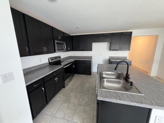 A kitchen features dark cabinets, gray countertops, and a stainless steel island sink — 4815 RIGGING STREET, HAINES CITY, FL