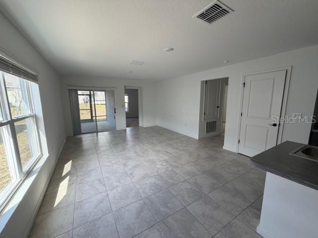 A bright, open-concept living area features light-colored tile flooring, white walls, and a sliding door — 4815 RIGGING STREET, HAINES CITY, FL