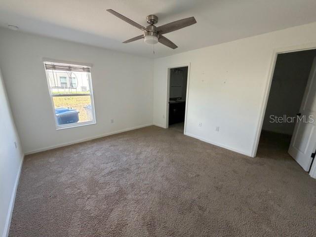 A bedroom with beige carpet, a ceiling fan, a window, and two doorways — 4815 RIGGING STREET, HAINES CITY, FL