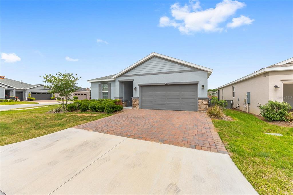 A single-story house with a gray exterior, stone accents, and a brick-paved driveway — 4537 NW 53RD COURT, OCALA, FL