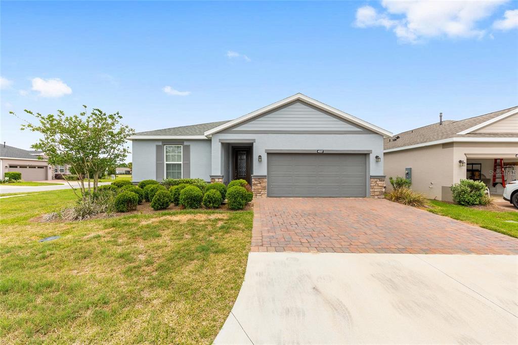 A single-story house with a gray exterior, a two-car garage, and a brick paver driveway — 4537 NW 53RD COURT, OCALA, FL