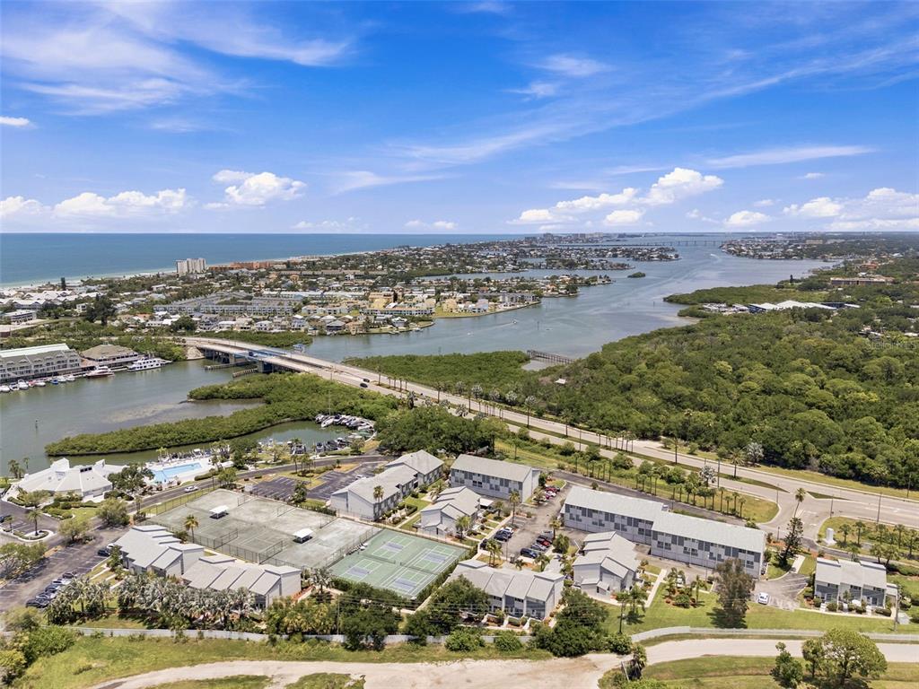 An aerial view shows a residential complex with tennis courts near a bridge and water — 14800 WALSINGHAM ROAD UNIT 702, LARGO, FL
