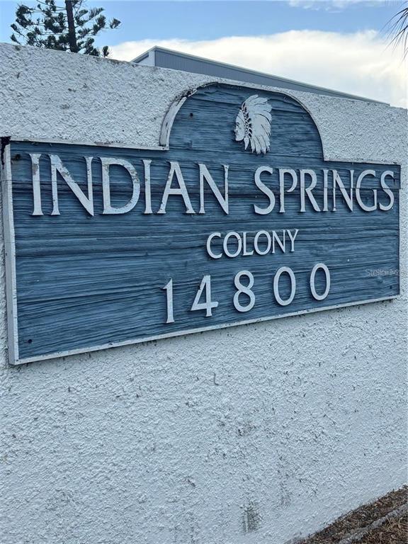 A blue wooden sign with white lettering reads Indian Springs Colony 14800 on a wall — 14800 WALSINGHAM ROAD UNIT 702, LARGO, FL