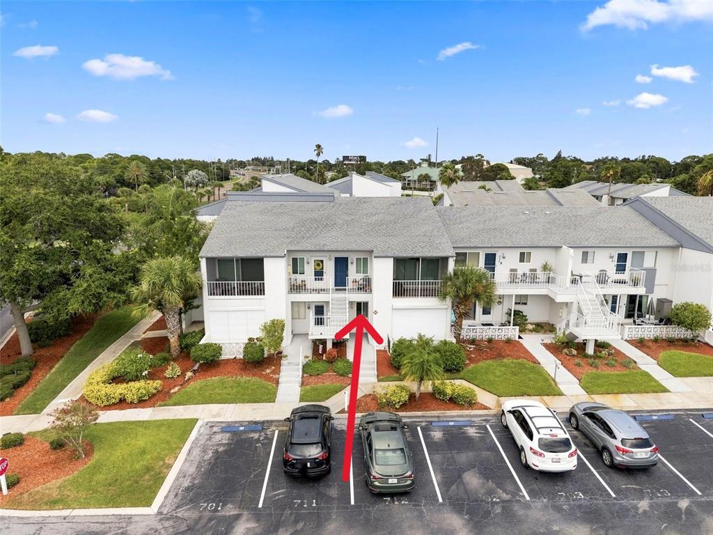 An exterior view of a two-story apartment building with a red arrow pointing toward a unit — 14800 WALSINGHAM ROAD UNIT 702, LARGO, FL