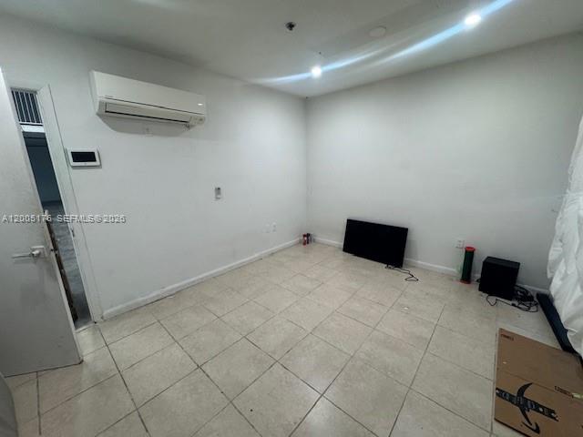 An empty room features white walls, tile flooring, a wall-mounted air conditioner, and a television — 13850 SW 143rd Ct # 18, Miami FL 33186, MIAMI, FL
