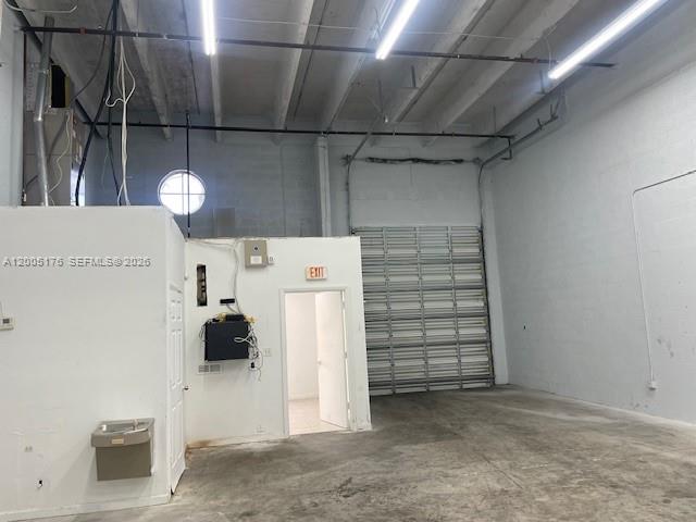 An industrial warehouse space features a concrete floor, high ceilings, and a roll-up door — 13850 SW 143rd Ct # 18, Miami FL 33186, MIAMI, FL
