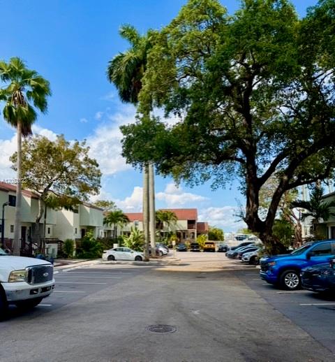 A paved parking lot sits between residential buildings and large trees under a blue sky — 1901 NW S River Dr # 22C, Miami FL 33125, MIAMI, FL