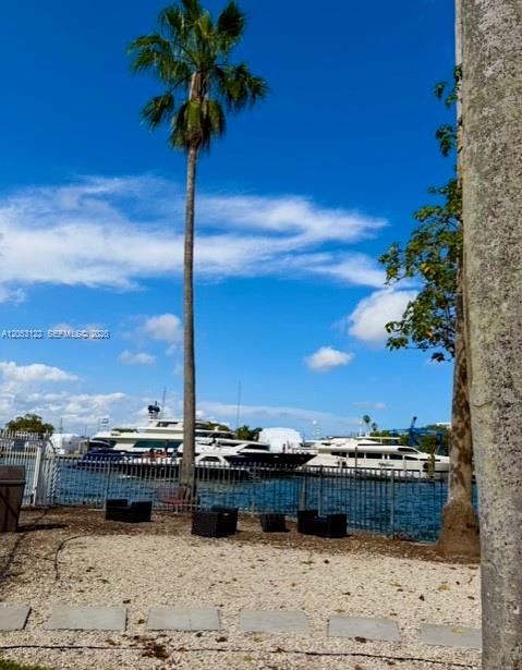 A palm tree stands near a gravel area overlooking a canal with several docked yachts — 1901 NW S River Dr # 22C, Miami FL 33125, MIAMI, FL