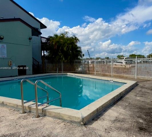 An outdoor swimming pool sits next to a building with a white metal fence — 1901 NW S River Dr # 22C, Miami FL 33125, MIAMI, FL