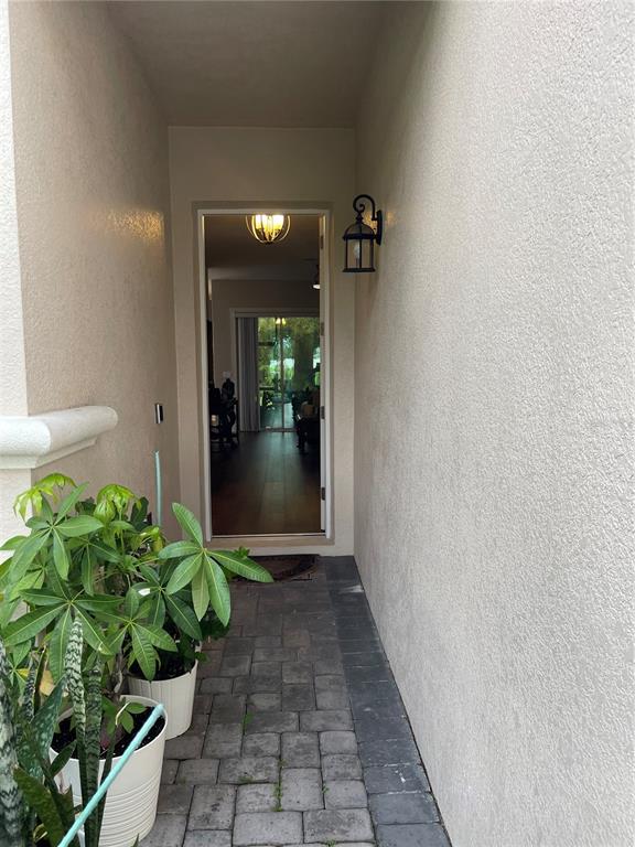 A paved entryway leads through an open doorway into a home with wood flooring — 2821 PLYMOUTH PLACE, KISSIMMEE, FL
