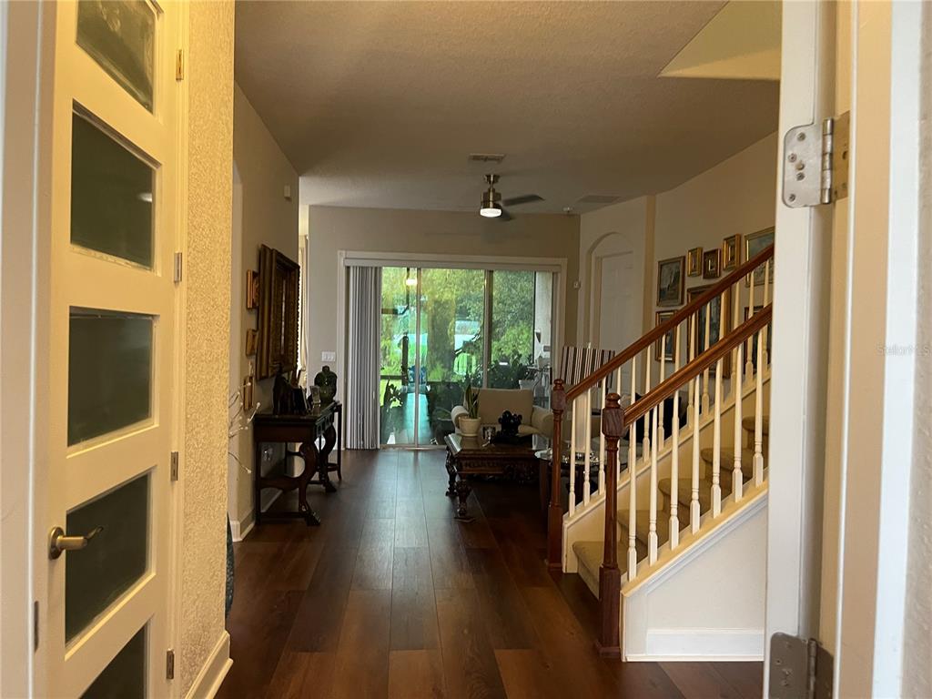 An entryway with dark wood floors leads to a living area with a sliding glass door — 2821 PLYMOUTH PLACE, KISSIMMEE, FL