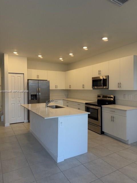A kitchen features white cabinetry, stainless steel appliances, and a central island with quartz countertops — HOMESTEAD, FL