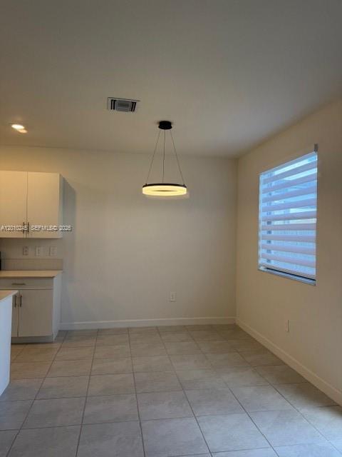 A dining area features light tile flooring, white cabinetry, and a modern circular pendant light — HOMESTEAD, FL