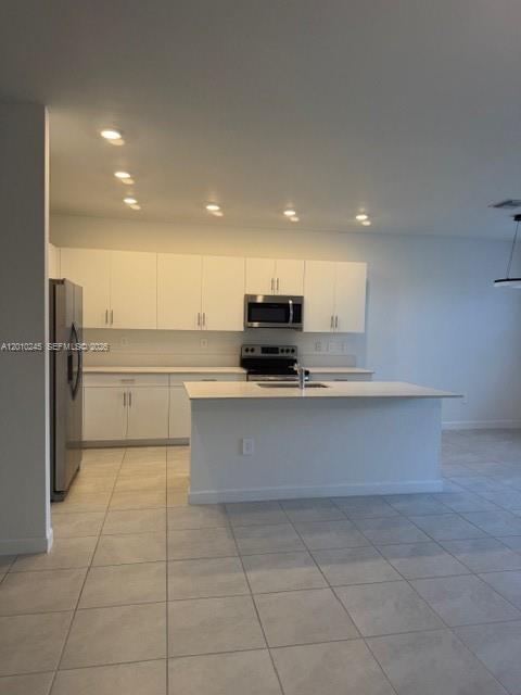 A modern kitchen features white cabinetry, stainless steel appliances, and a central island — HOMESTEAD, FL